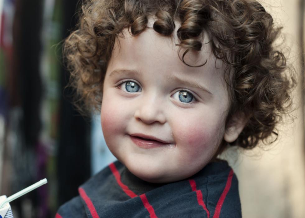 Baby boy with big blue eyes and curly hair.