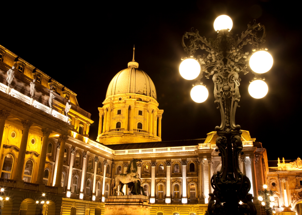 A large, ornate illuminated building with a white facade and a central dome.