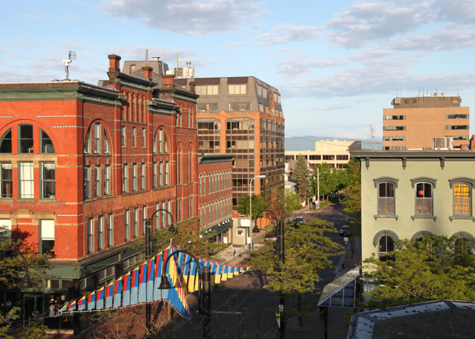 Bright red tall buildings on the left along the city street and green building on the right side.