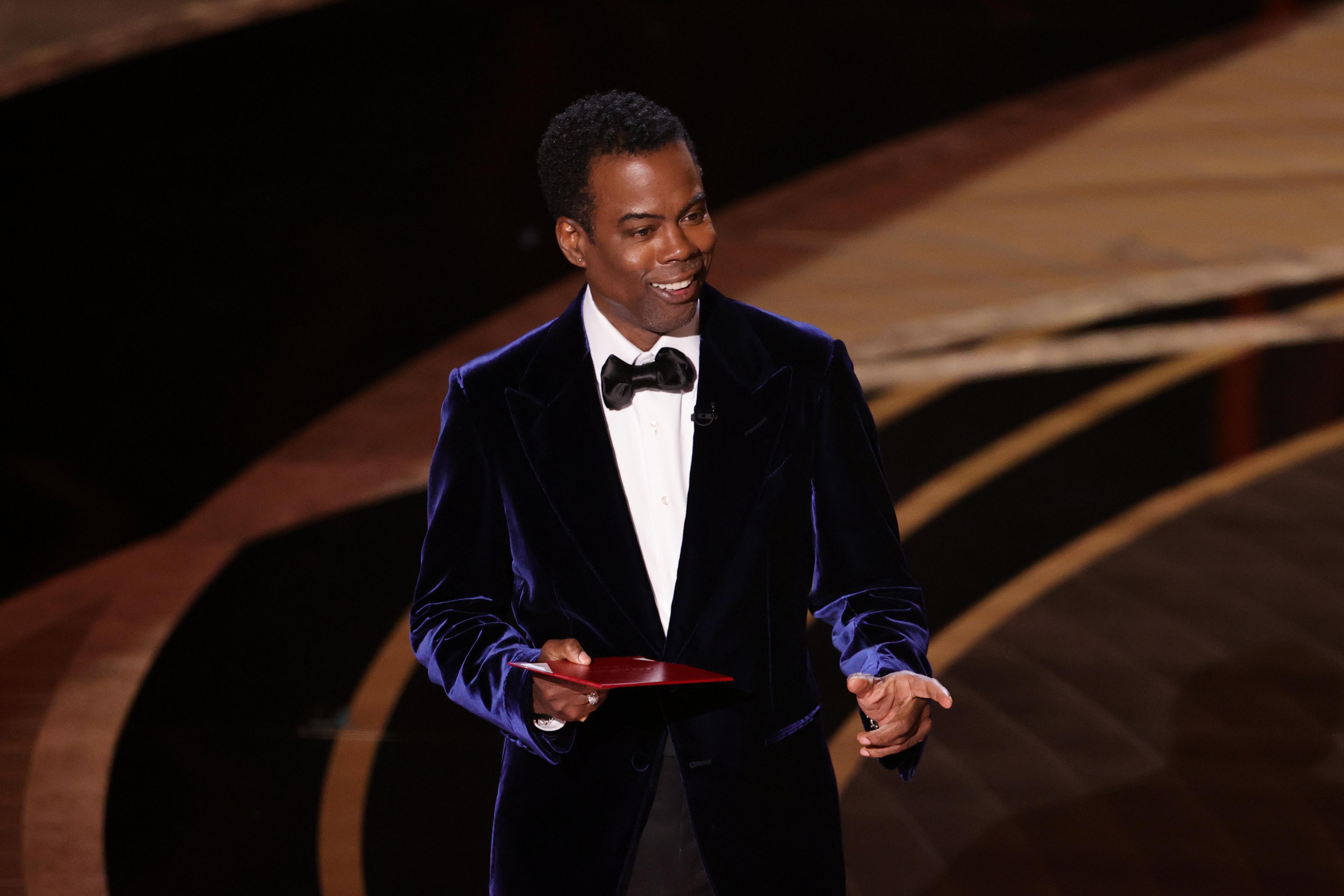 Chris Rock in a blue velvet suit on stage.