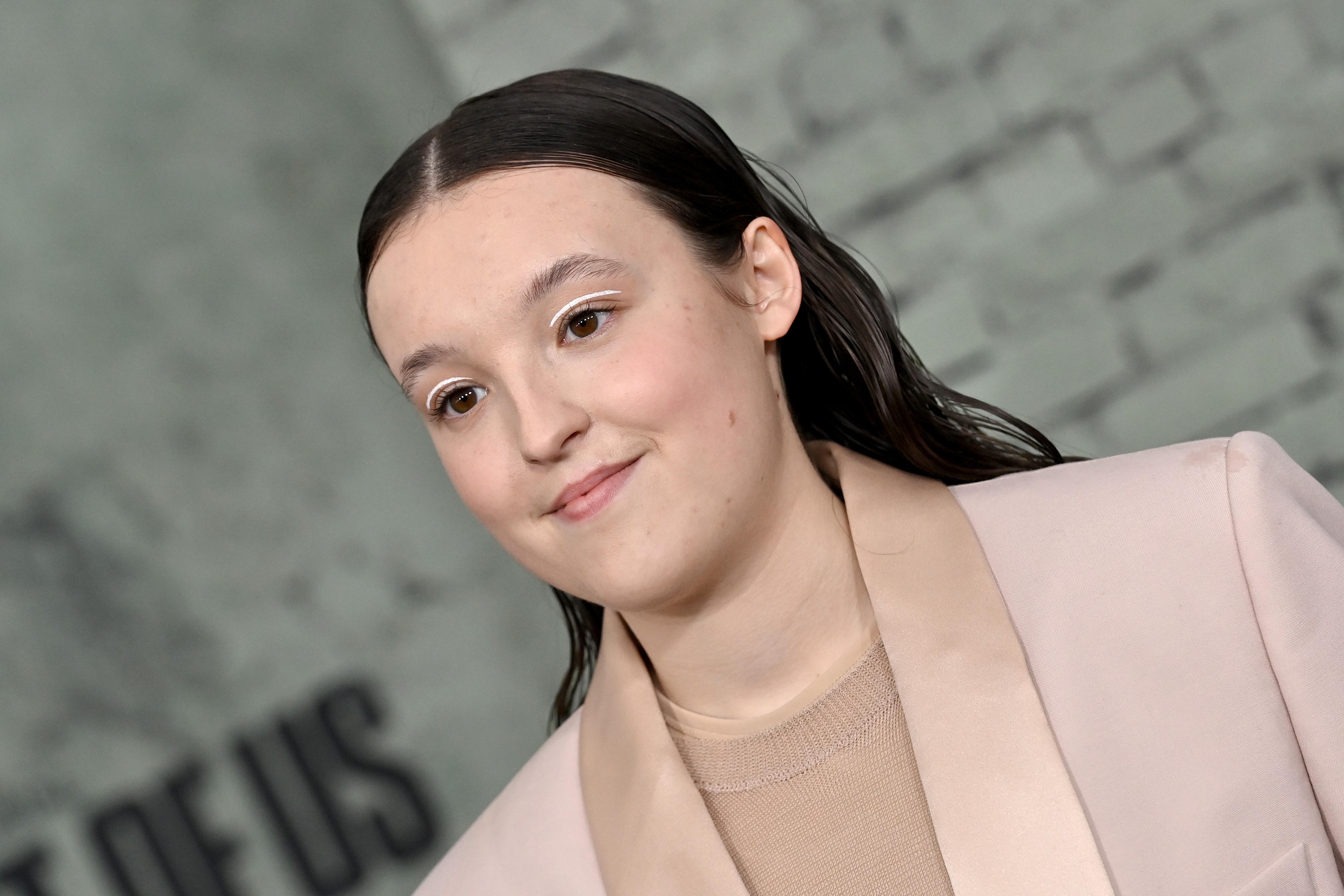 Bella Ramsey in a pale pink suit.