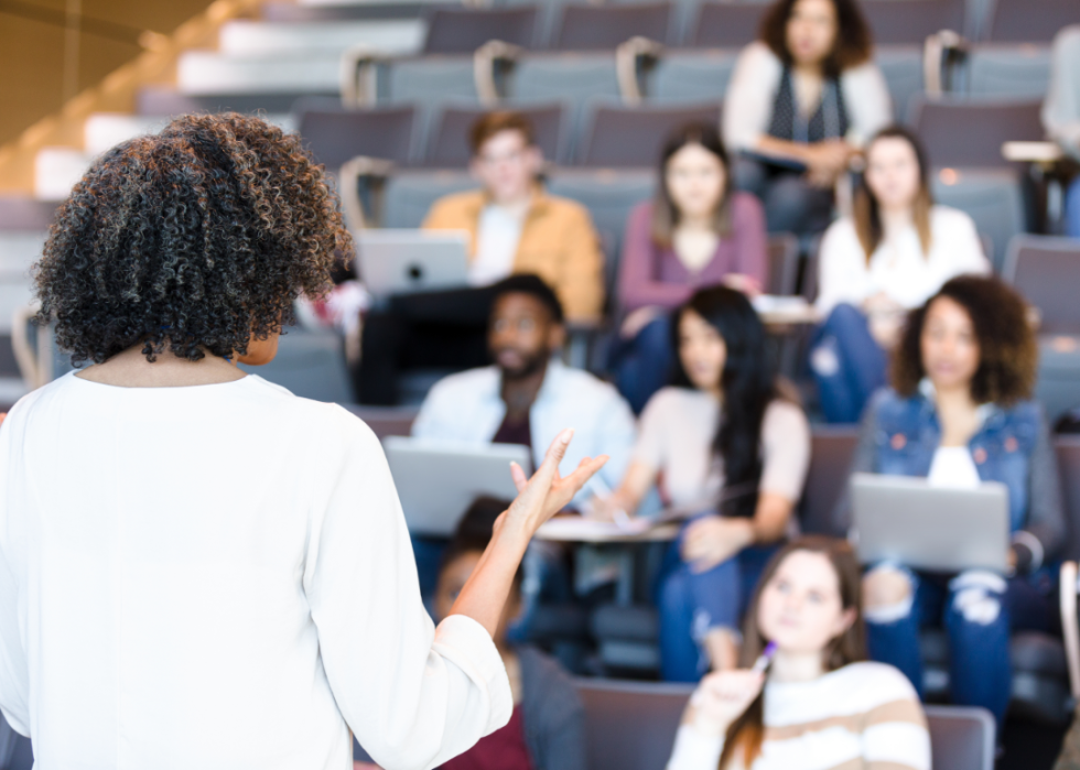 The back of a teacher who is instructing a group of students in front of her.