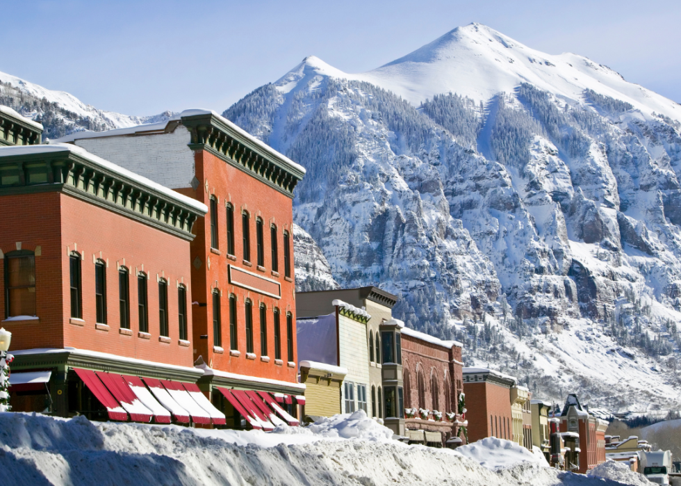 Tall snowy mountains surrounding a town with lots of snow on the street.
