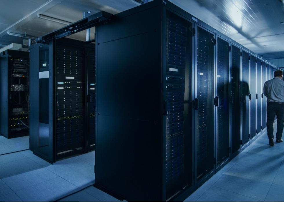 A sillouhette of a man's back surrounded by black racks with equipment.