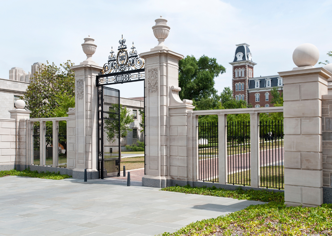 A stone wall with an iron fence in front of University of Arkansas.