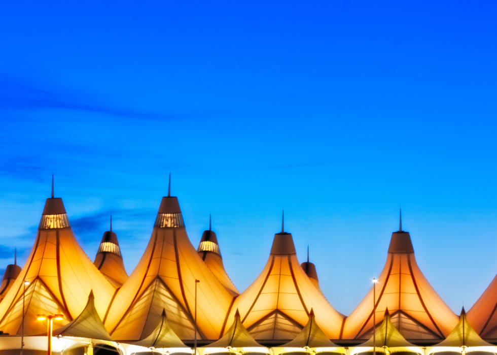 A close up of a distinctive, tent-like roof of the Denver airport building lit intended to mimic the snow-capped peaks of the Rocky Mountains.