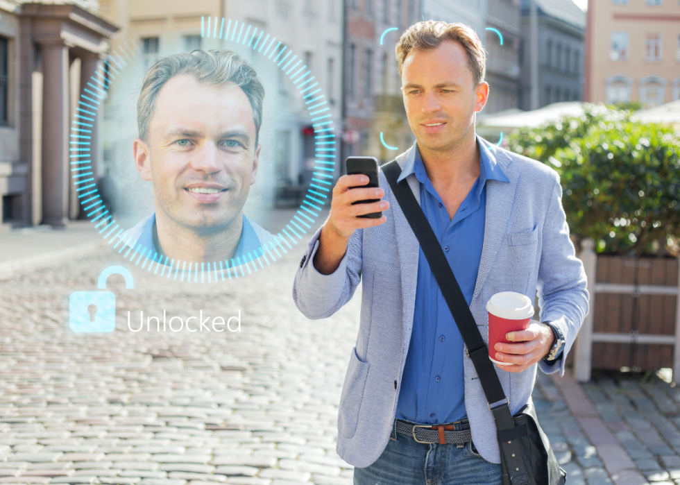 A man holding a phone in his hand with a close up of his face next to him.