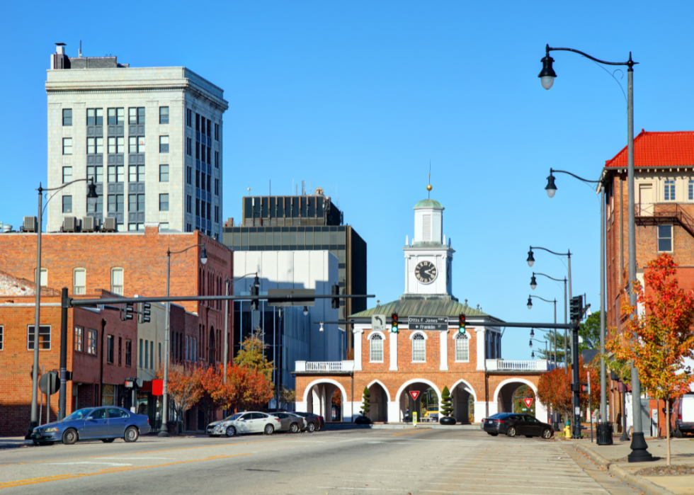 Red brick buildings along the street with a tall white building in the background.