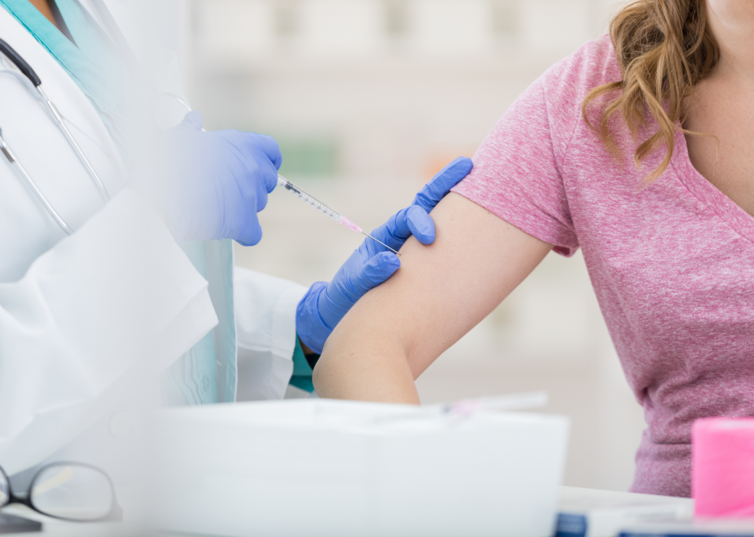 A nurse injects a flu vaccine into a woman's arm