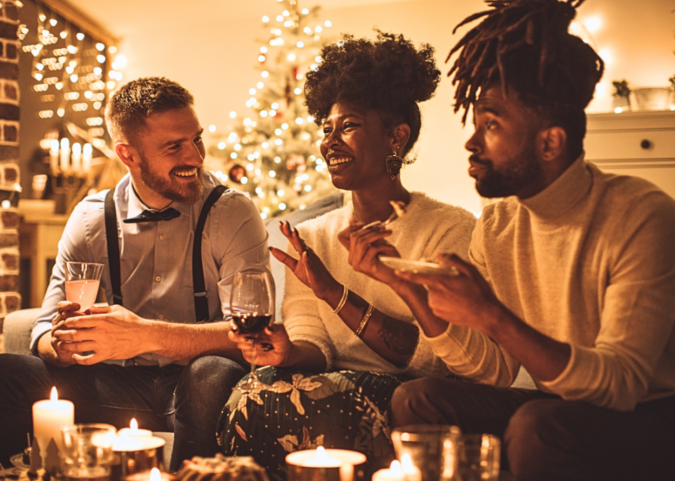 A group of people sitting at the coffee table decorated with candles, holding drinks.