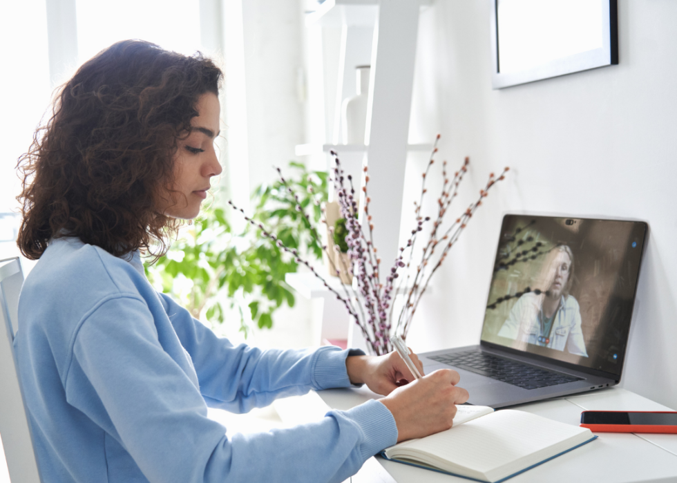 A young girl sitting in front of the computer participating in a video call for distance learning.