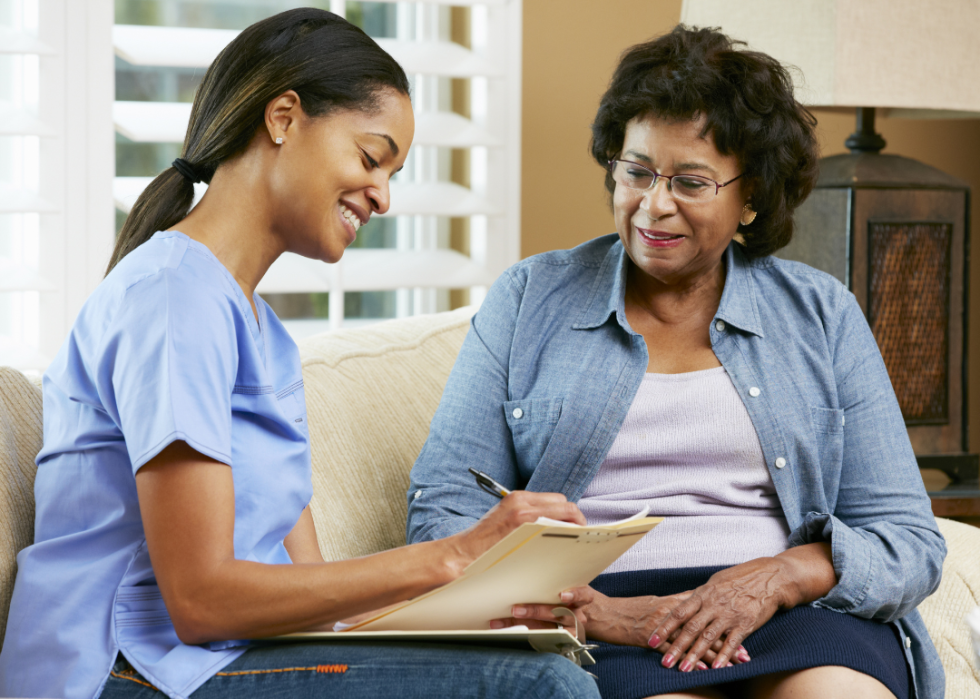 A nurse taking notes while sitting next to a patient.