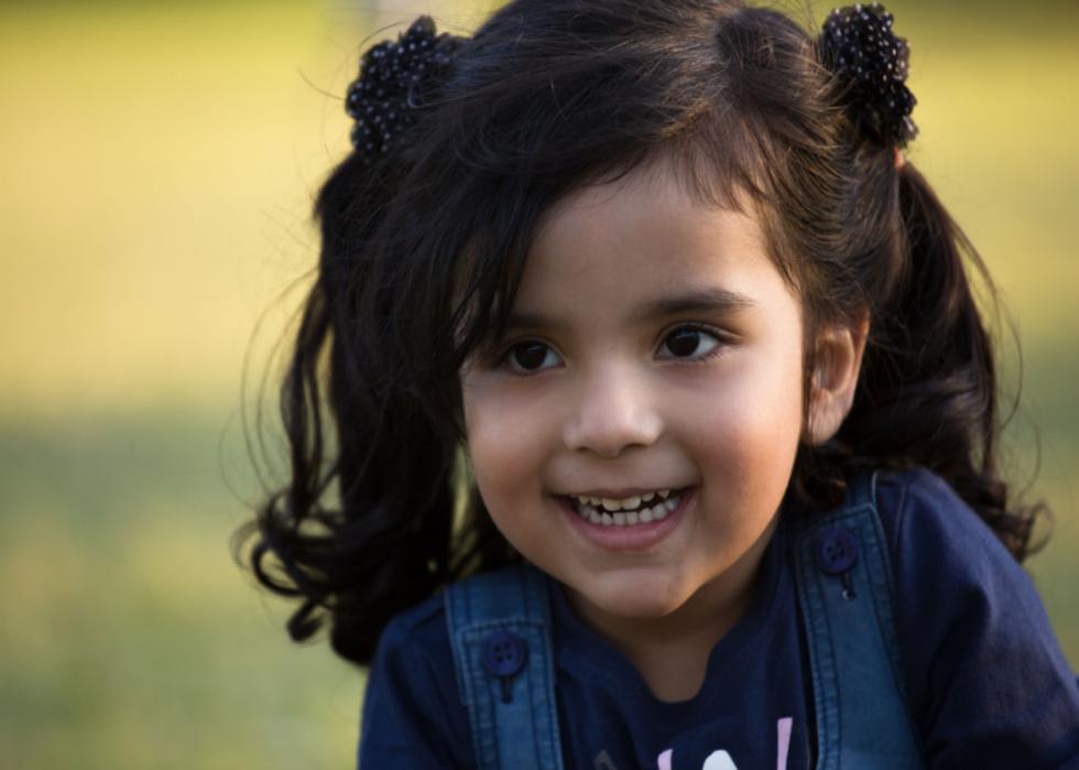 Smiling Hispanic girl with long ponytails.