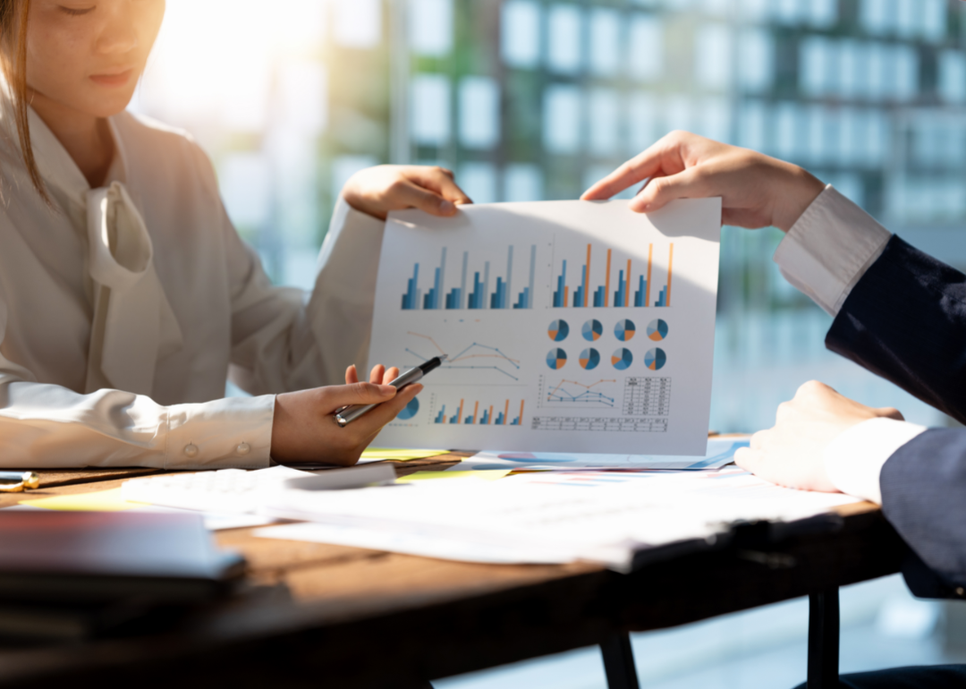Two women review investment data in an office setting