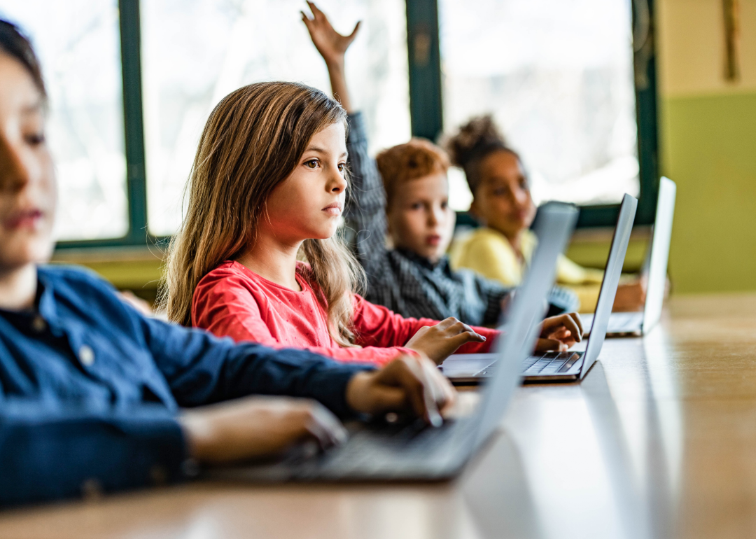 Young children in a classroom setting with laptops.