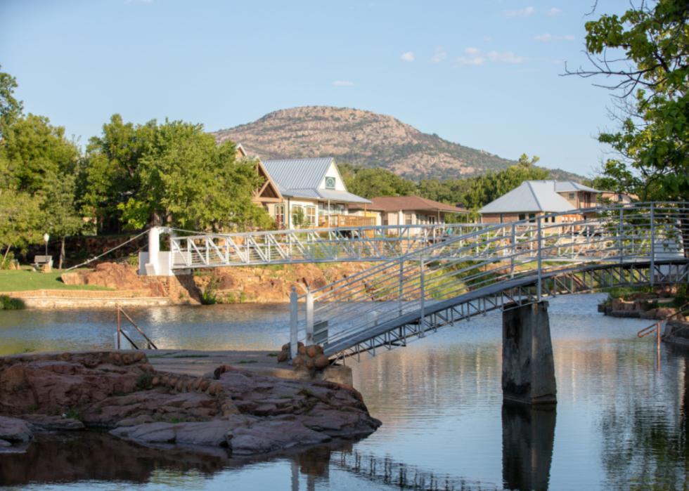 A bridge stretching across a river with a tall mountain in the background.