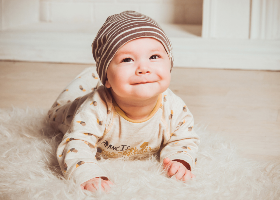 A baby boy in a hat crawling. 