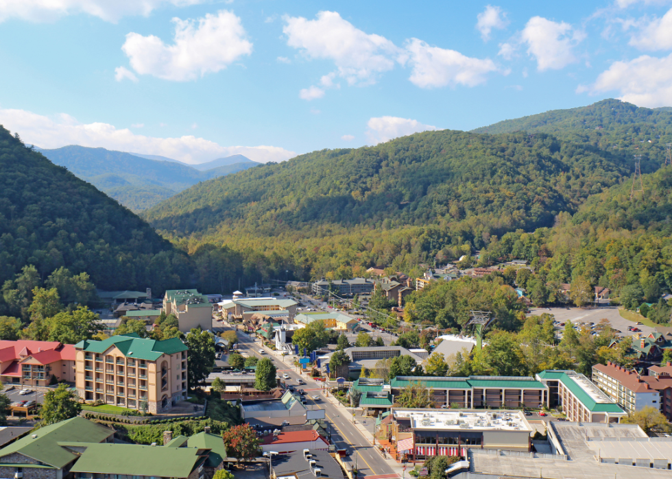Main road in a small town with tree-covered mountains surrounding it.