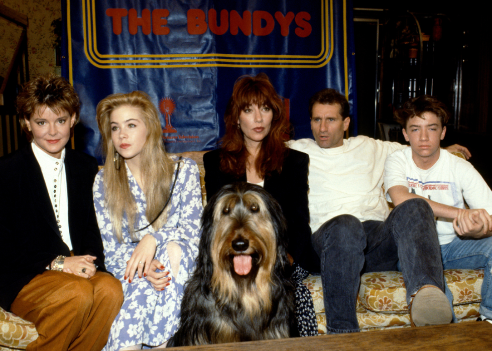 The cast of Married... with Children, Amanda Bearse, Christina Applegate, Katey Segal, Ed O'Neill, and David Faustino pose for a portrait with their dog Buck, circa 1990.