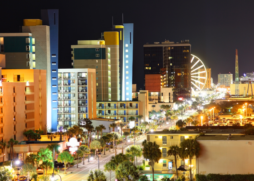 A city of skycrapers and tall buildings at night with a large Ferris wheel brightly lit.