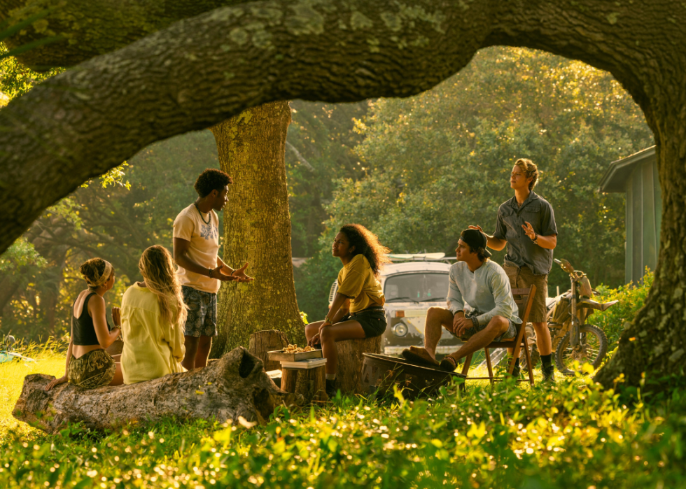 A group of young people talking under a tree.