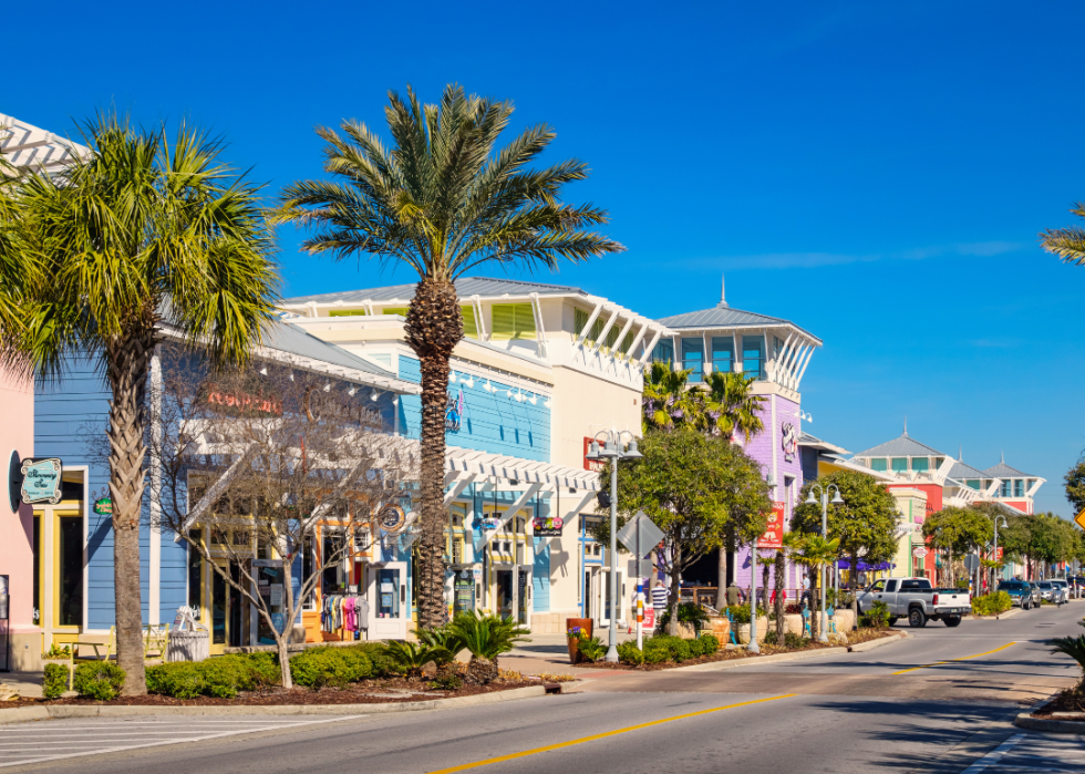 A street lined with colorful shops and tall palm trees.