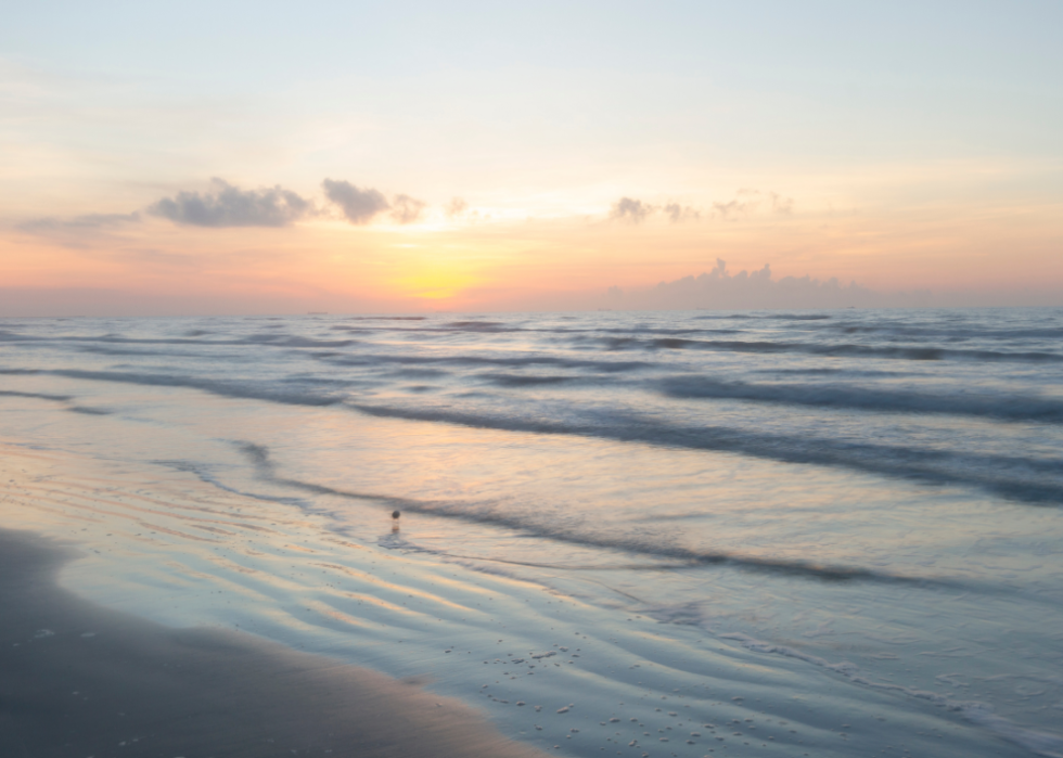 Waves lapping at the shore of a beach at sunrise.