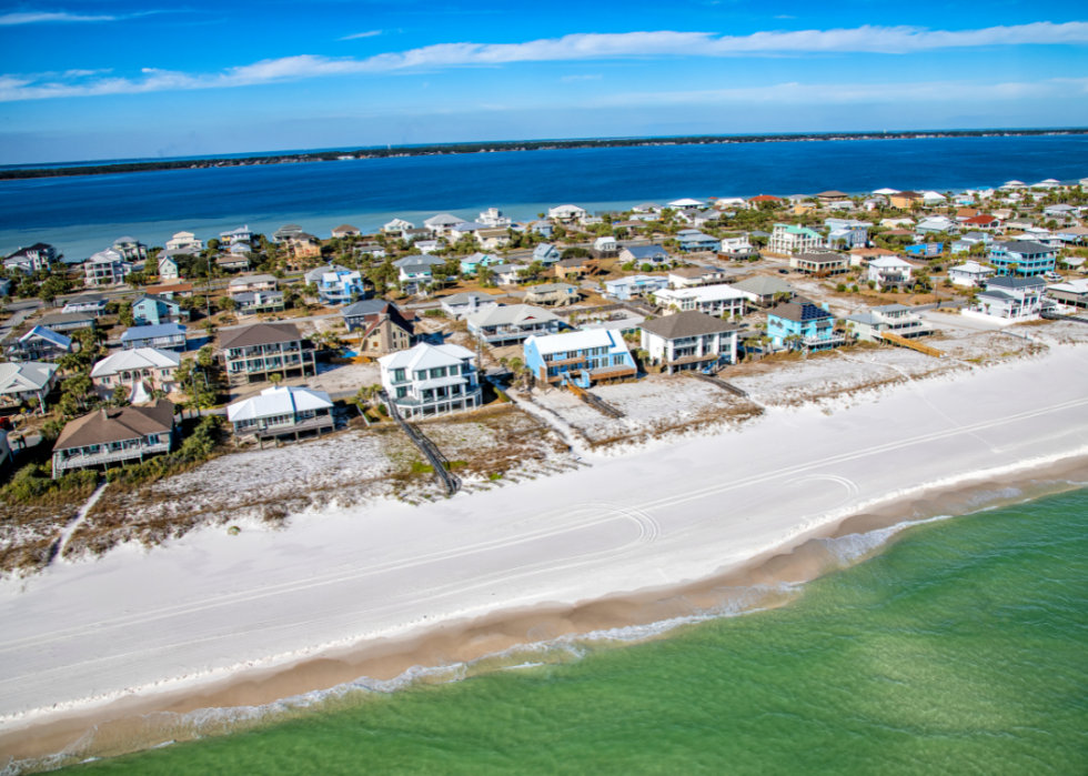 A row of houses on a beach next to the ocean.