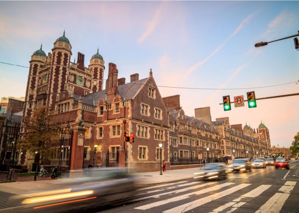 A large, red-brick building with traditional, ornate details. A busy street in the foreground.