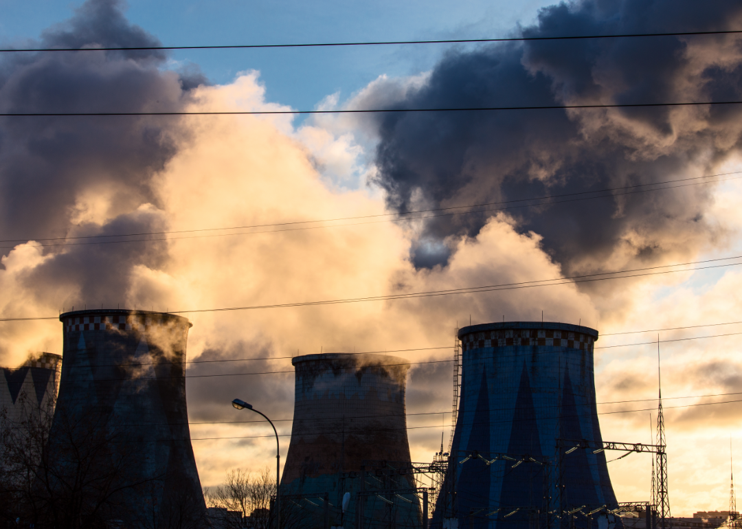 Smokestacks emanating pollutants at sunset.