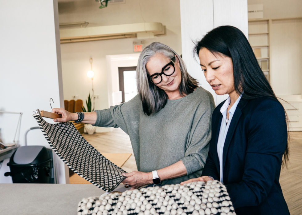 A retailer showing fabric samples to a client in a showroom.