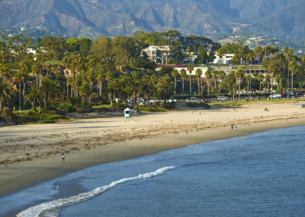 A beach with palm trees and mountains in the background.