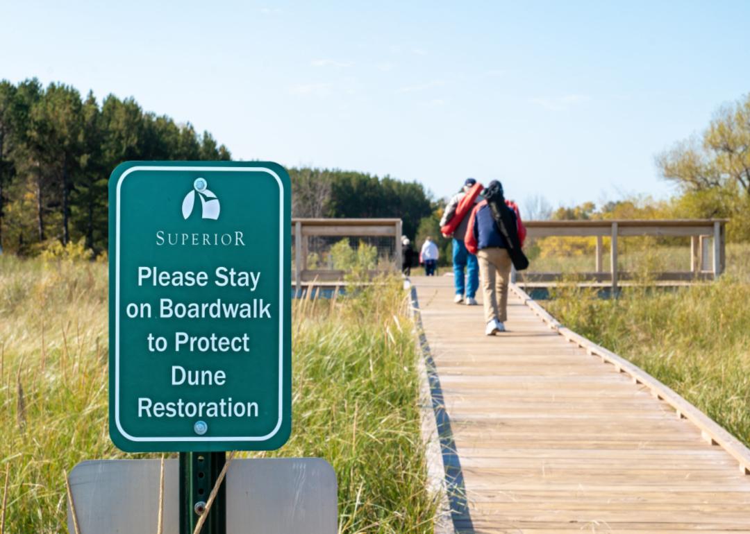 People walking on a boardwalk over a dune.
