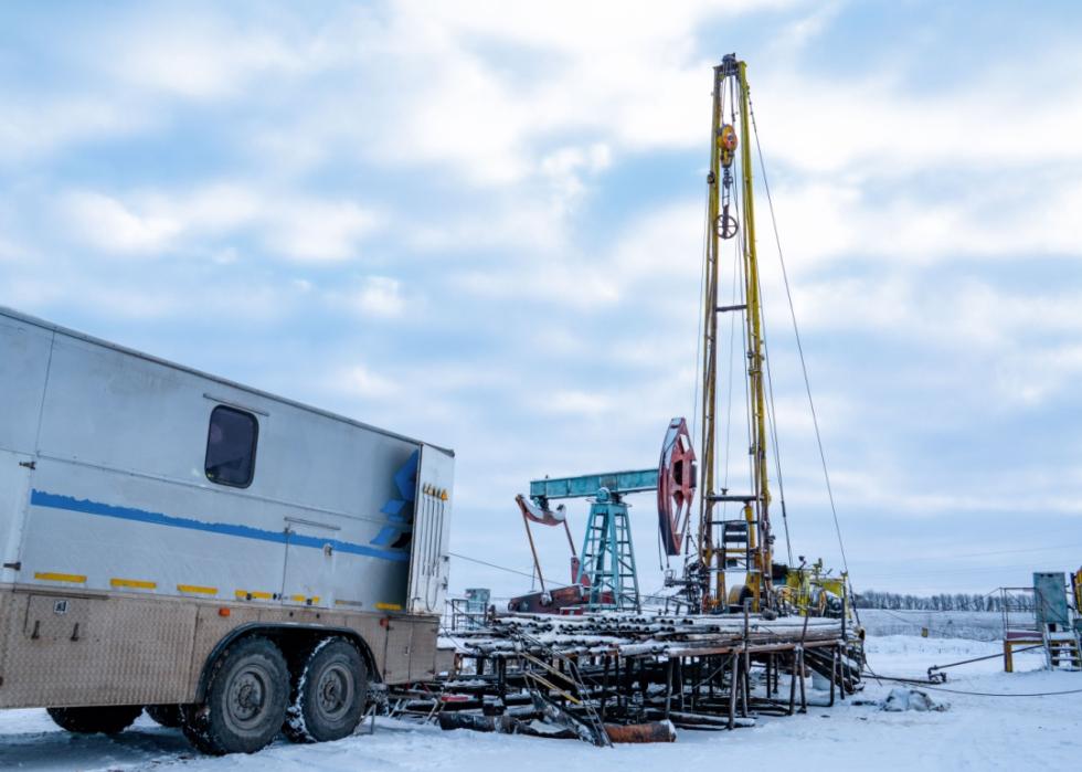 A heavy, tall machinery covered in snow and a trailer parked close by.