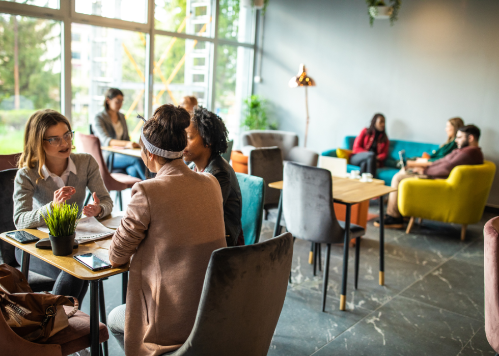 Co-workers meeting in colorful chairs in an open room with big windows.