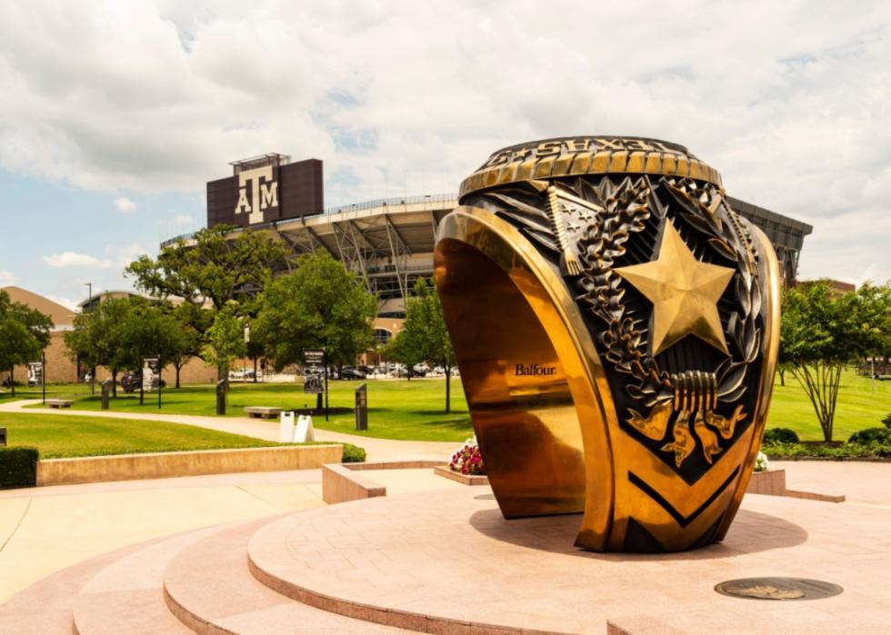 A statue of a giant college ring and the Texas A&M stadium.