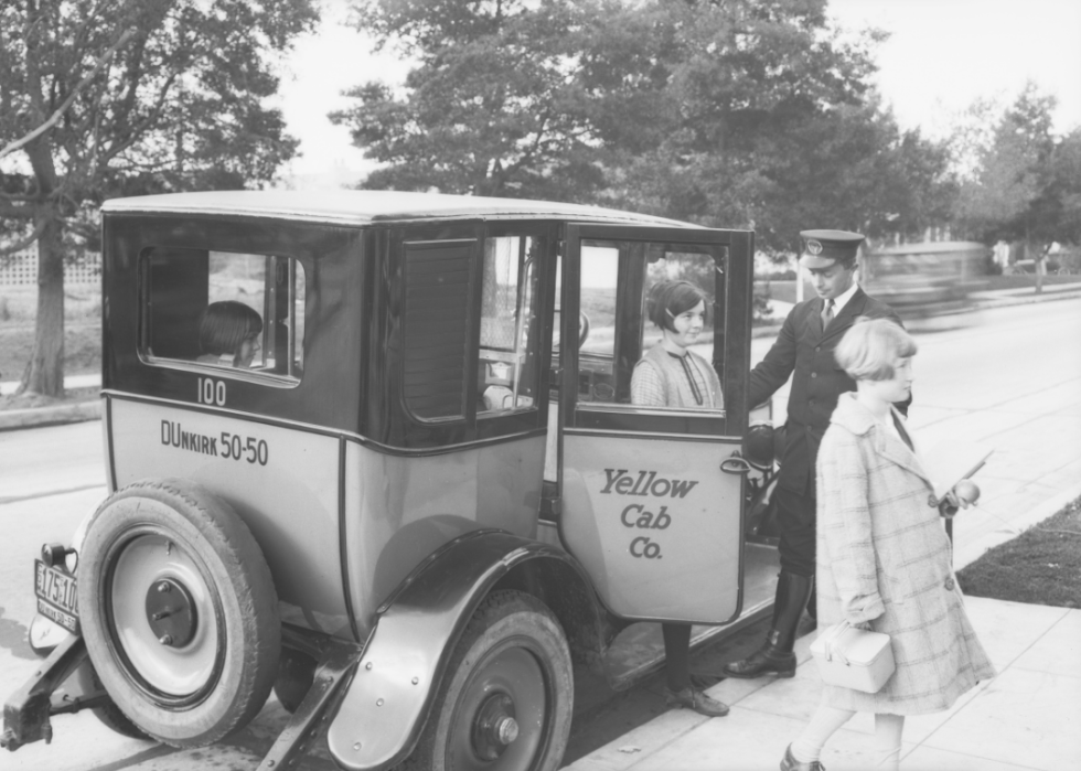 A cabbie assists two young girls emerging from his cab