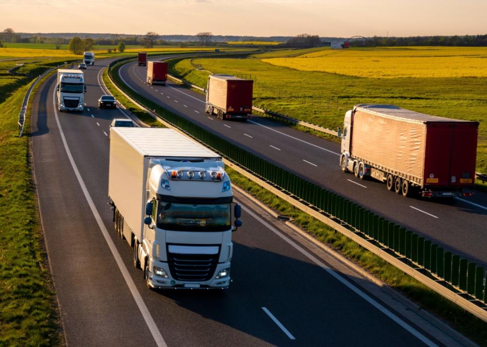 Truck traffic on the highway going in both directions among green flat land.