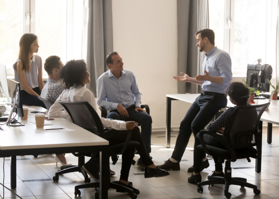 A group of people talk in an office environment.