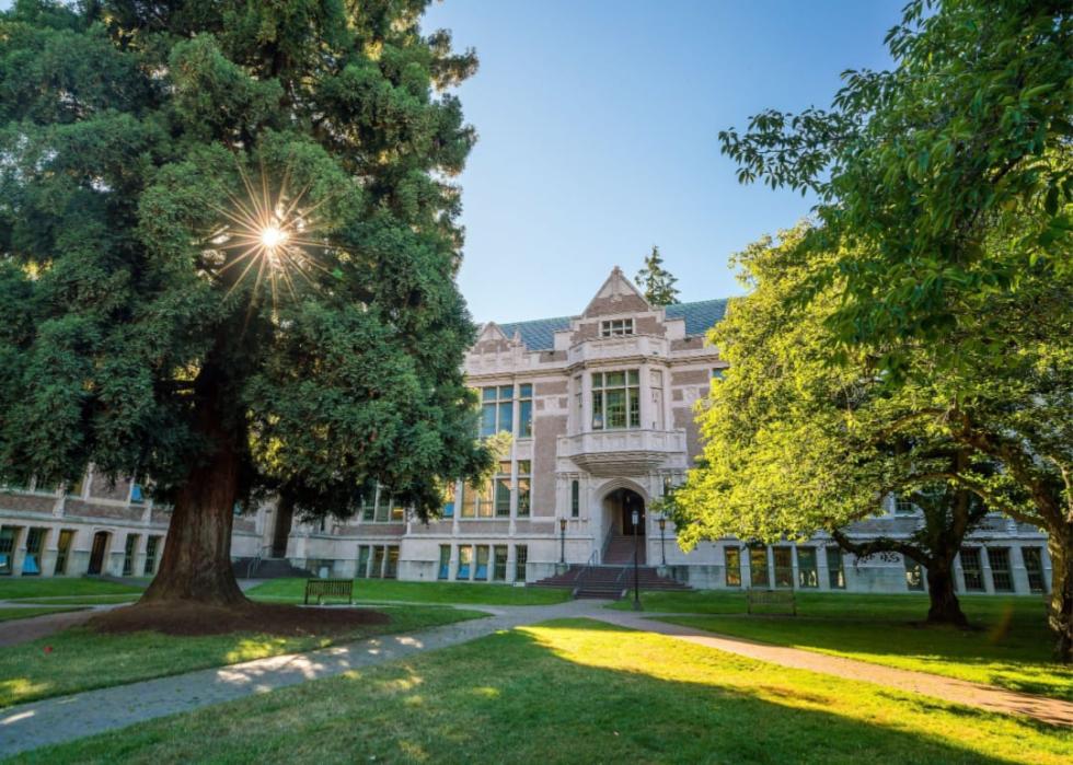 A  gray stone building surrounded by mature trees.