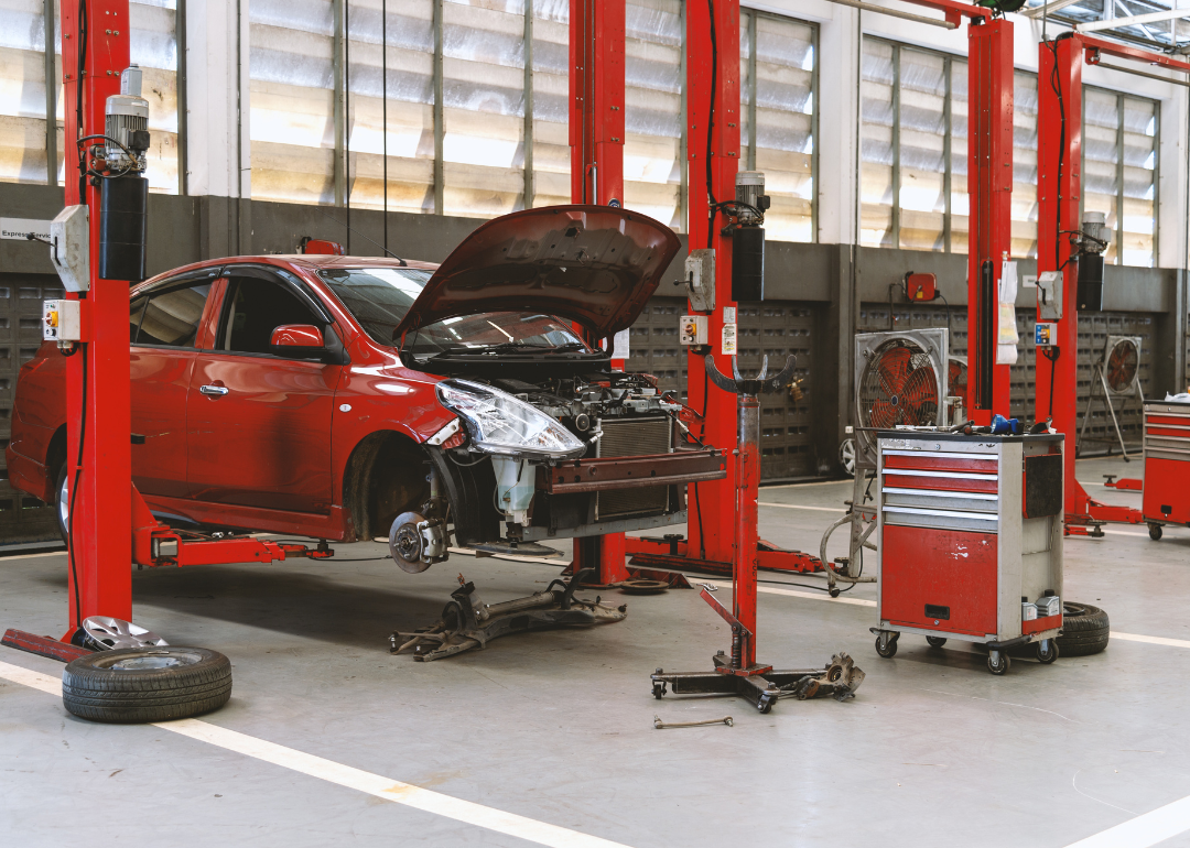 A damaged red car in an auto repair station.