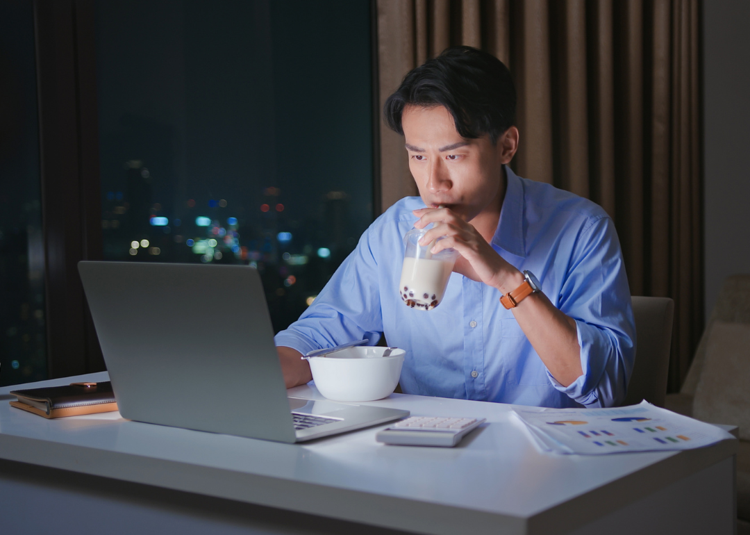 A person working from home at night while eating dinner.