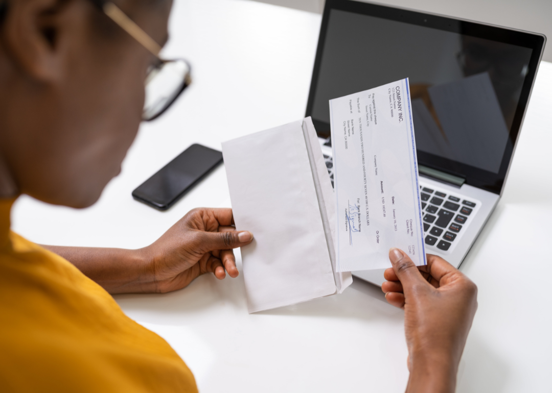 A person opening an envelope containing their paycheck.