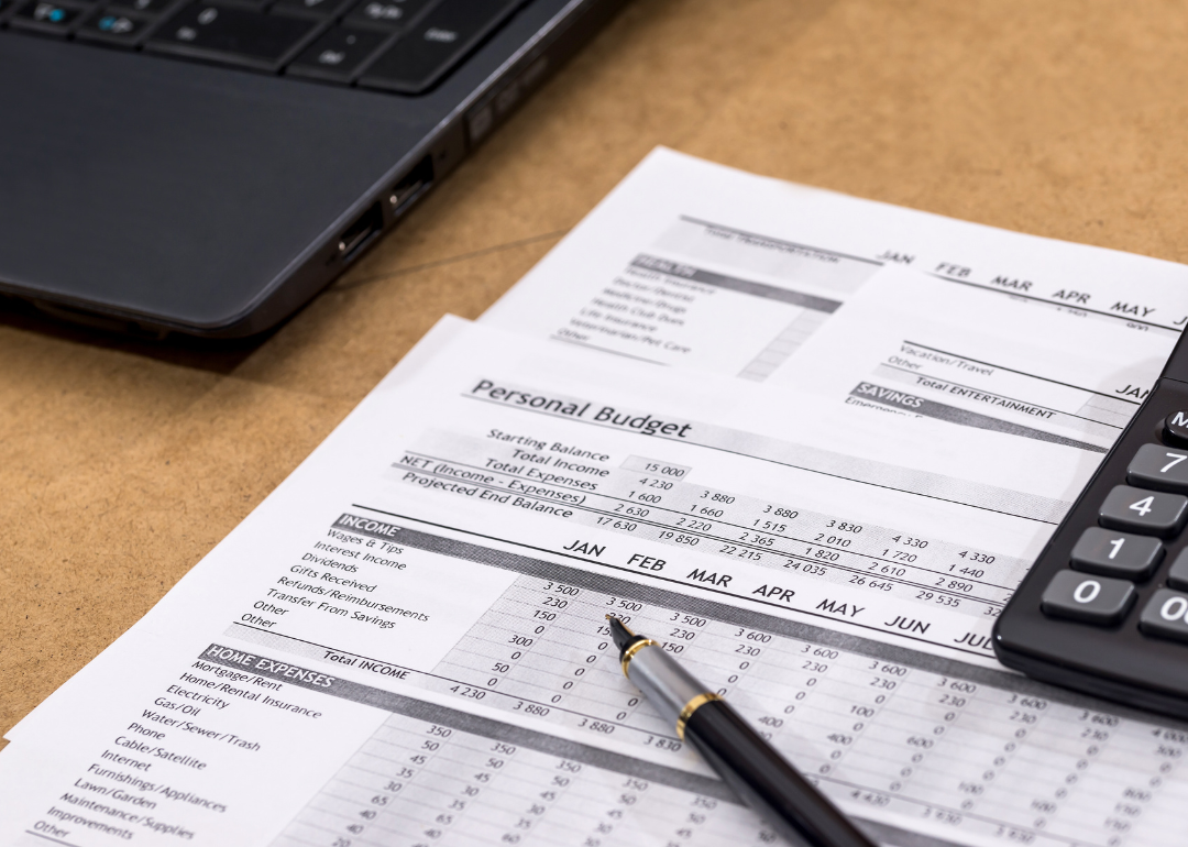 A detailed personal budget with a laptop next to it.