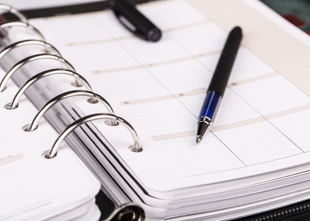 A blank calendar with a pen sitting on top of it.