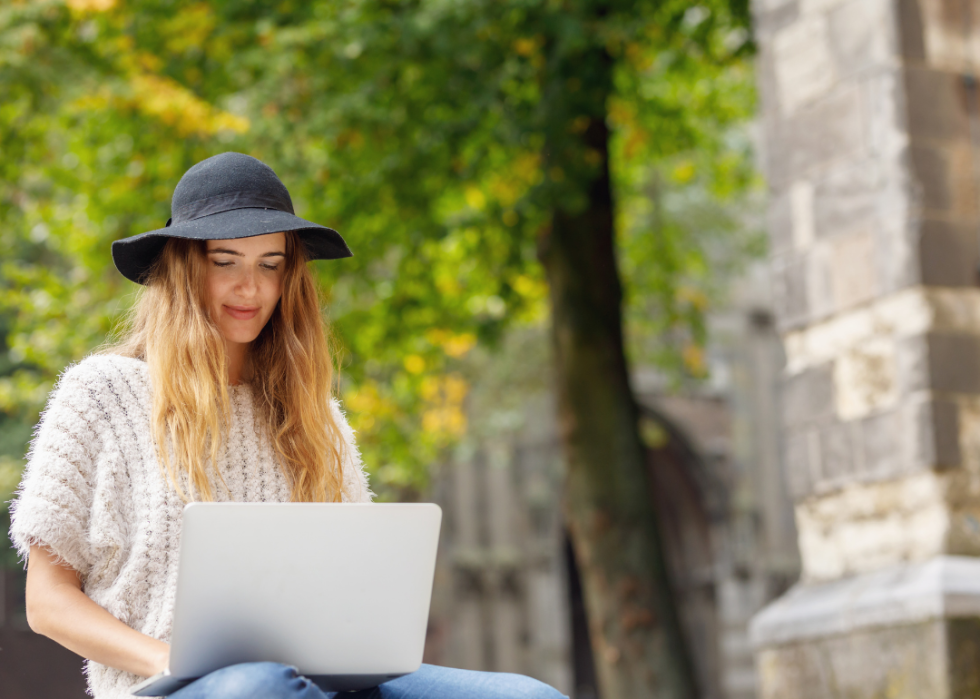 A college student working on her laptop outside