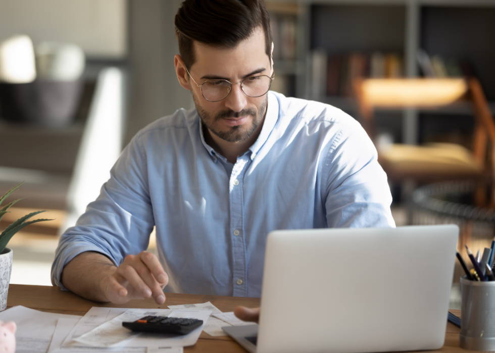 An accountant working on his laptop with a calculator