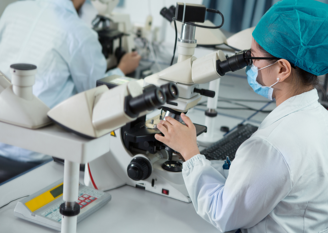 A scientific researcher looking into a microscope.