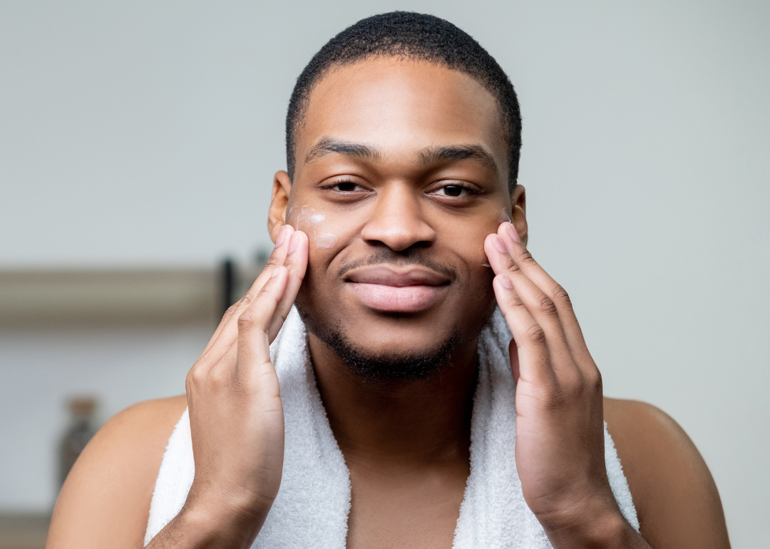 A person applying skin cream in the bathroom.