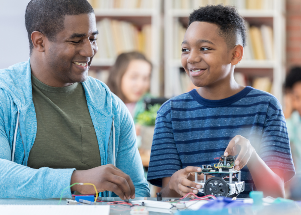 A mentor and junior high student discussing a robotics project and laughing